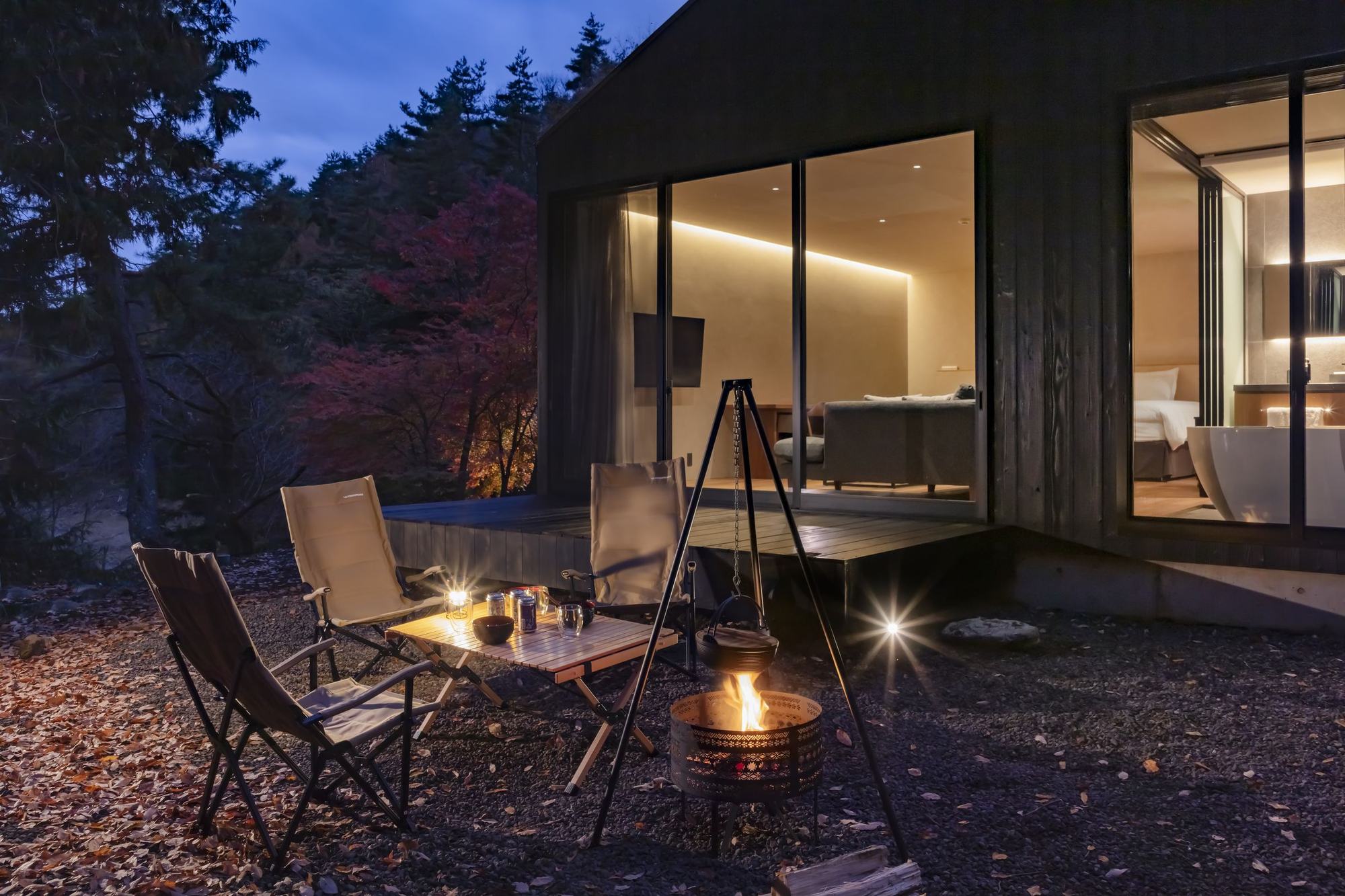夕暮れの森に灯る一棟の邸宅とテラス